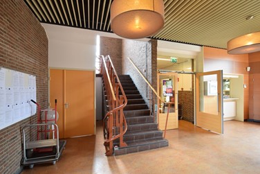 <p>Overzicht van het centrale trappenhuis in de hal. De ruimte onder de trap is opgevuld met een berghok, recent is ook de plafond- en wandafwerking gemoderniseerd. </p>
